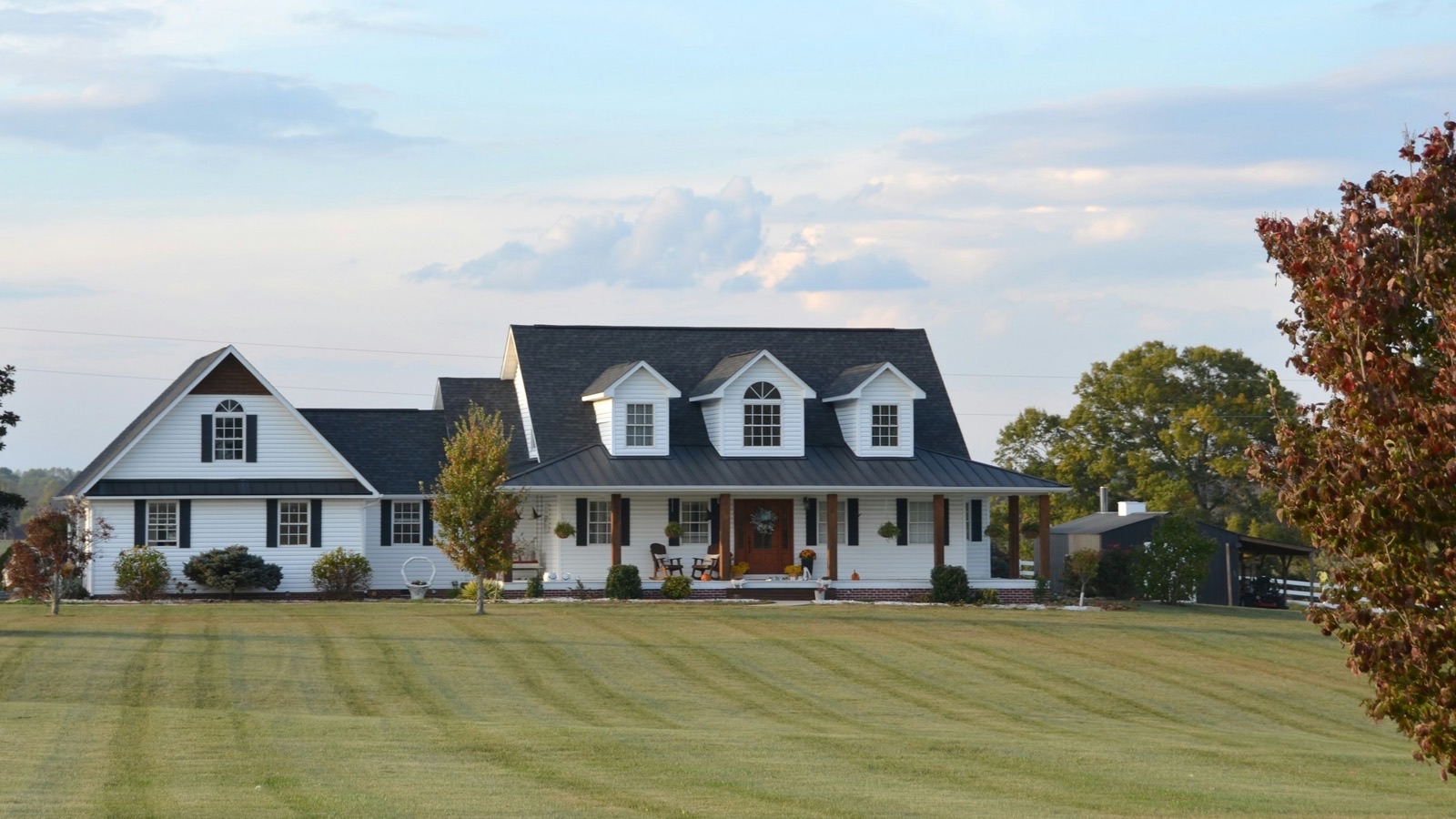 White farmhouse with dormer windows behind a wide mown lawn